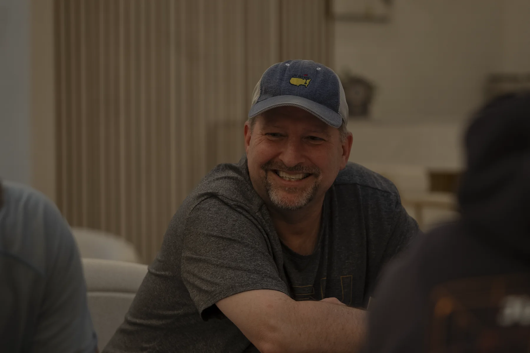 Brad Barton smiling at a table, wearing a cap